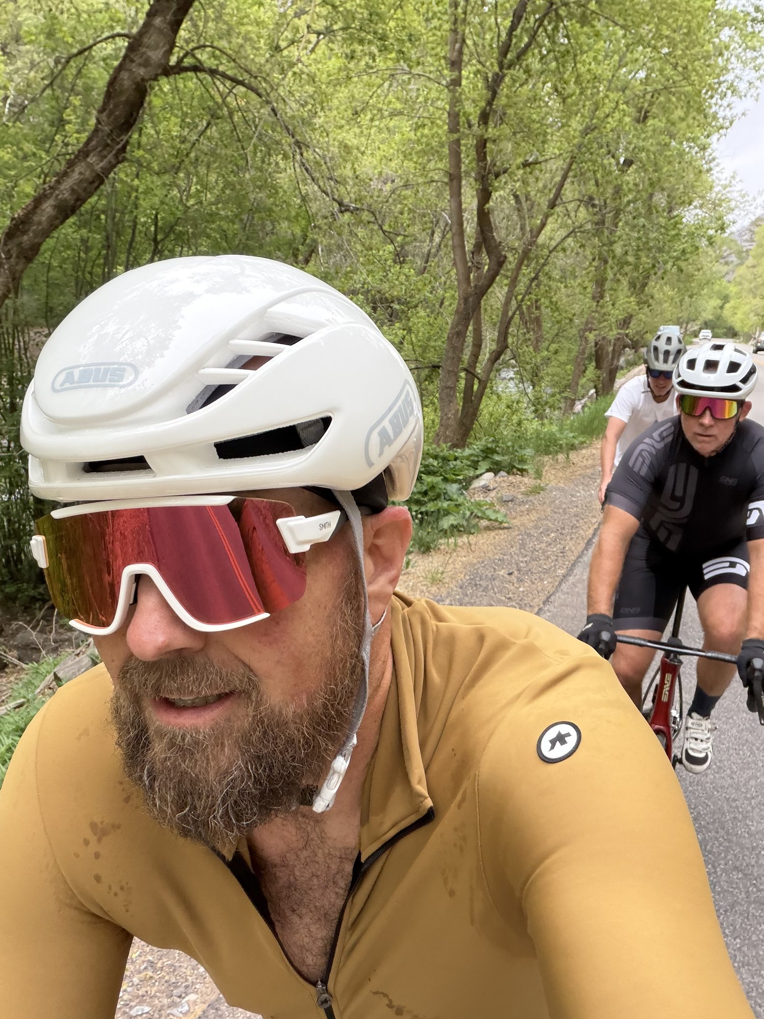 Ryan selfie riding through trees with Seth behind